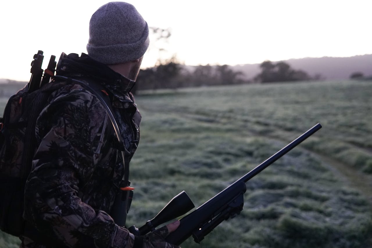 Cazador con rifle en el campo al amanecer durante la temporada de caza en España